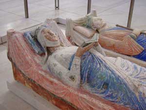 Le gisant couché d'Aliénor (avec Henri II au second plan), à Fontevraud : représentée à une trentaine d’années, coiffée de la couronne royale